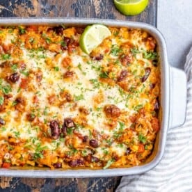 White casserole dish with Mexican chicken and rice casserole topped with melted cheese.