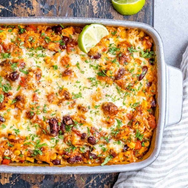 White casserole dish with Mexican chicken and rice casserole topped with melted cheese.