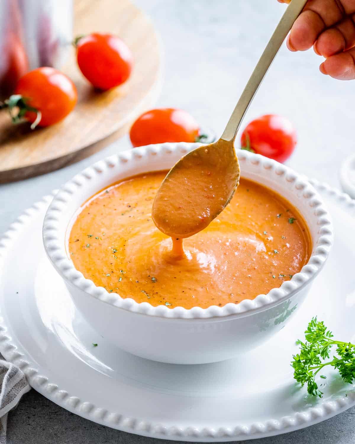 a bowl full of tomato soup with a spoon in the bowl dipping soup in bowl.