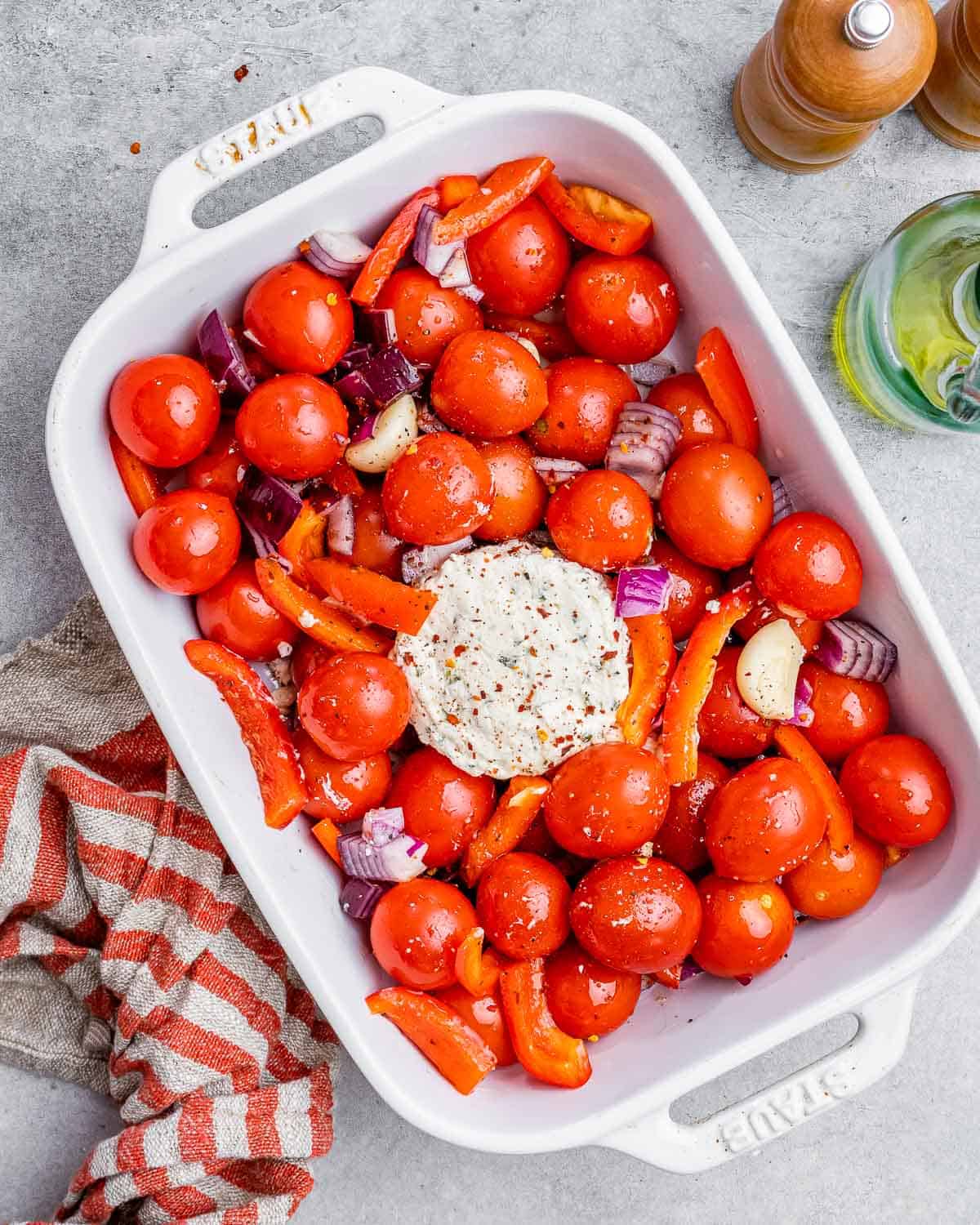 Boursin cheese added to the middle of the tomatoes in a white dish.