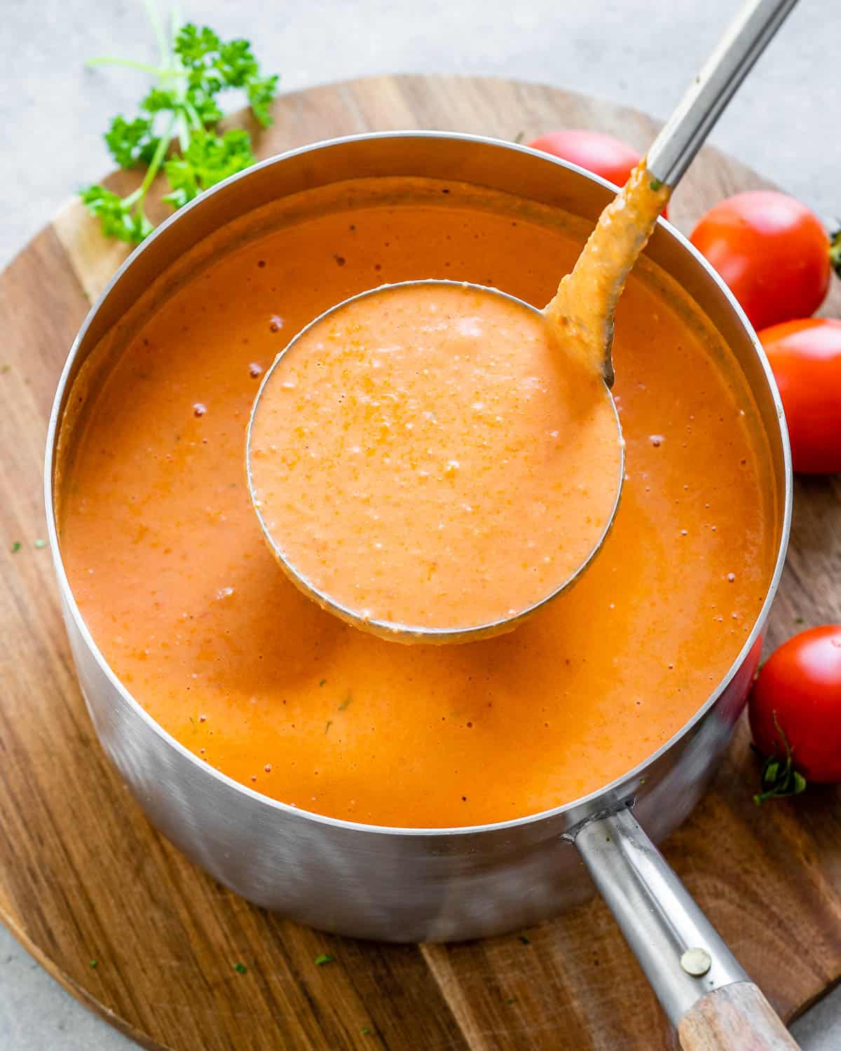 a pot full of tomato soup with a ladle full of soup being served from the pot.