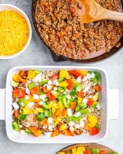 stuffed pepper casserole in white baking dish topped with rice, cheese, and bell peppers