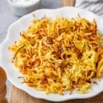 crispy-looking air fryer hash browns on a white plate.