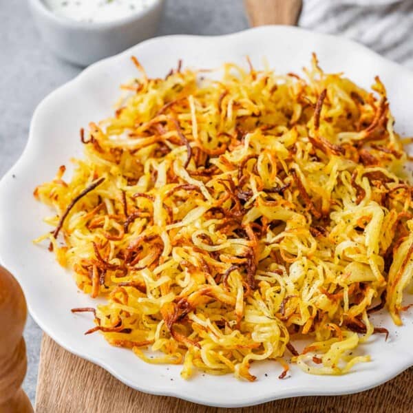 crispy-looking air fryer hash browns on a white plate.