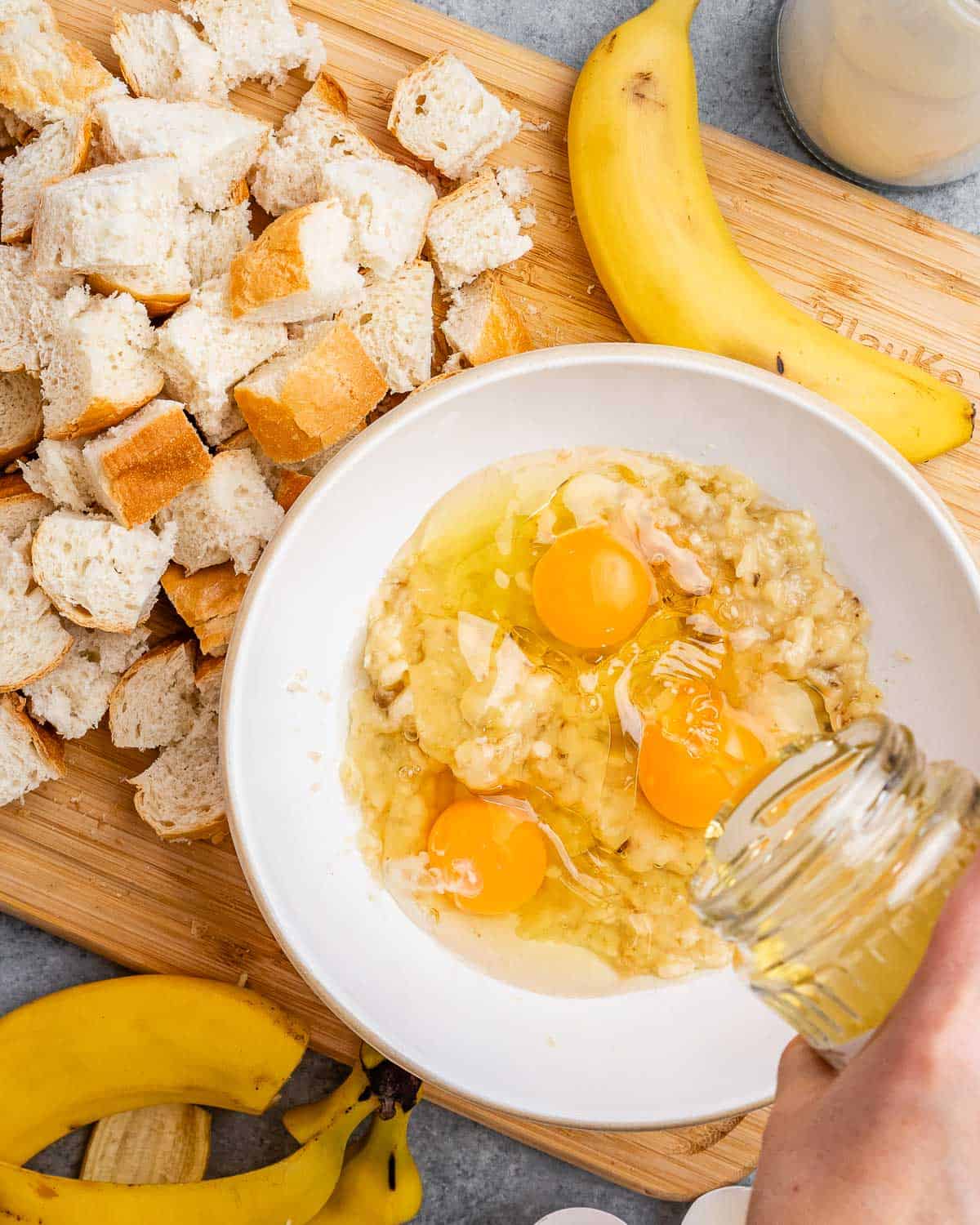 eggs being added over the mashed bananas in a bowl.