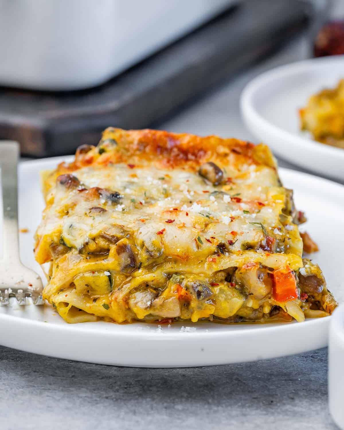 Close-up of a slice of baked butternut squash lasagna showing creamy layers of noodles, vegetables, and cheese.