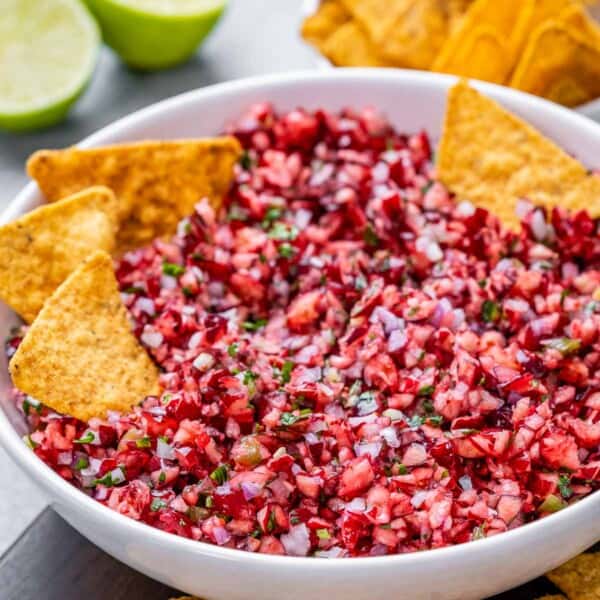 a bowl with cranberry salsa and a few tortilla chips in the bowl.