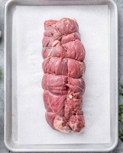 Raw tied roast beef on a tray, ready to be seasoned and roasted in the oven.