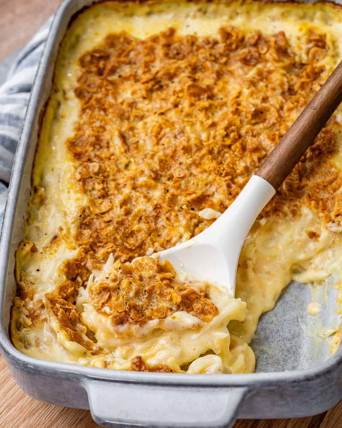 Creamy hash brown casserole in a dish with a spoon.
