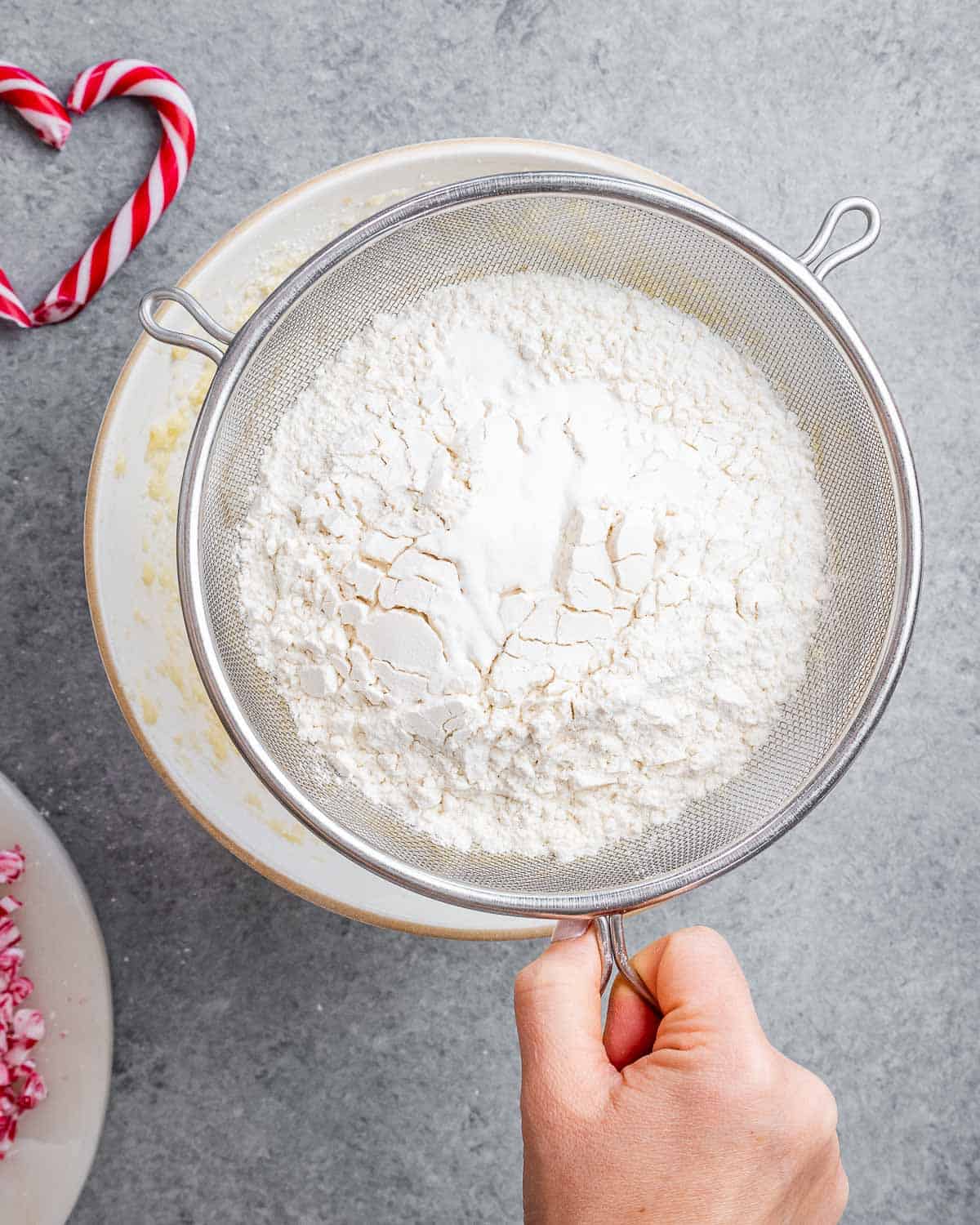 flour being sifted over the fluffy egg and sugar mixture.