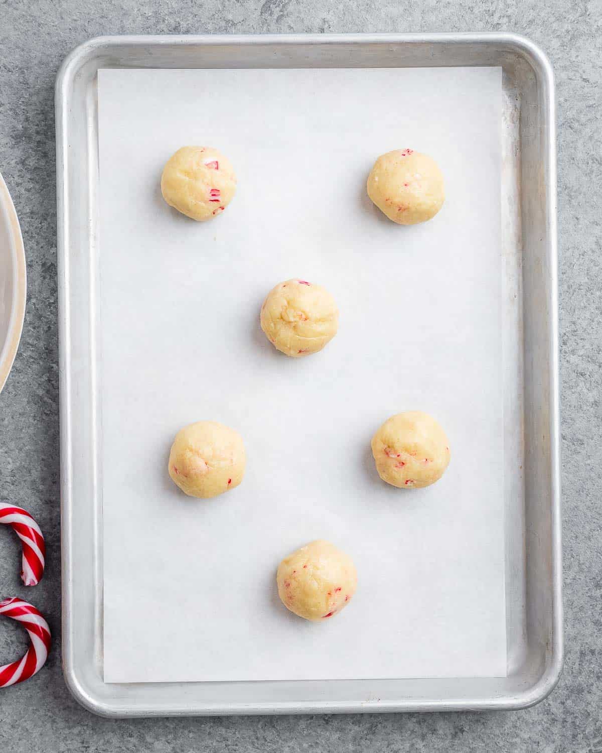 cookie dough balls placed on a sheet pan before baking.