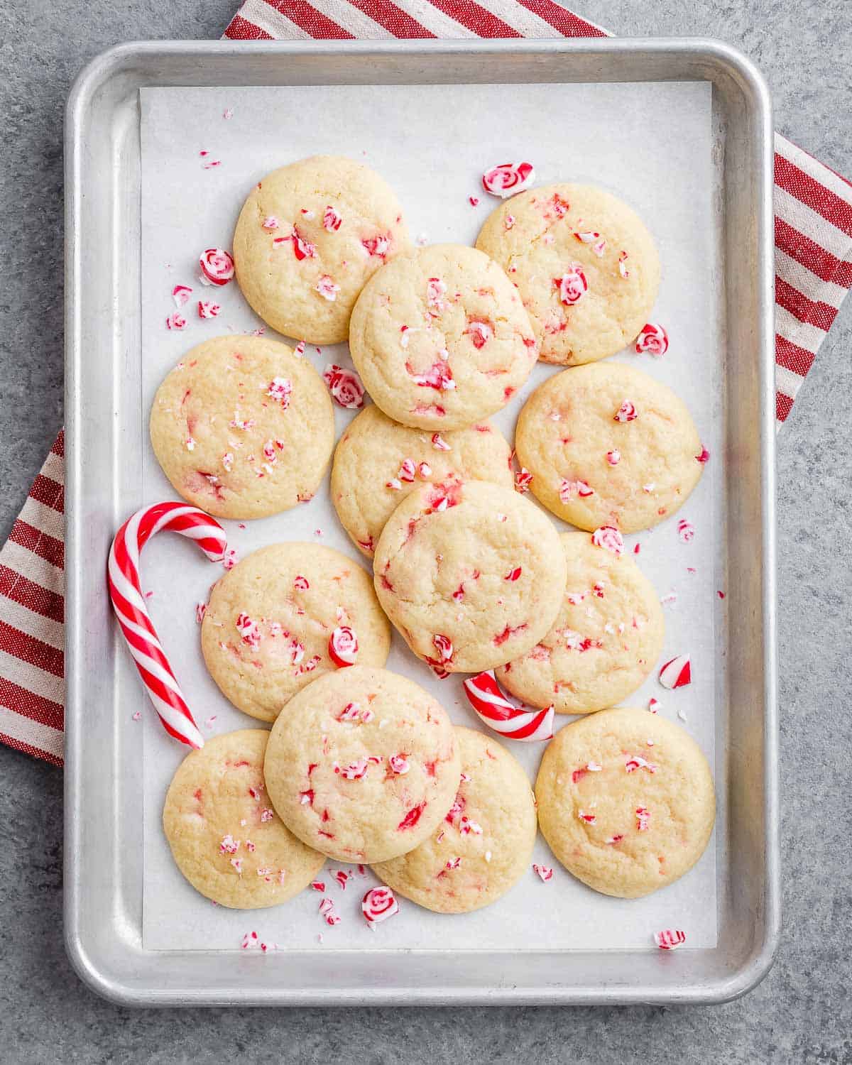 a sheet pan with peppermint cookies and a candy cane next to the cookies.