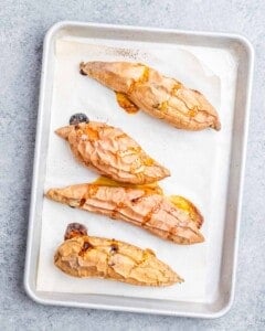 Baked sweet potatoes on a sheet pan, caramelized and soft, fresh from the oven.