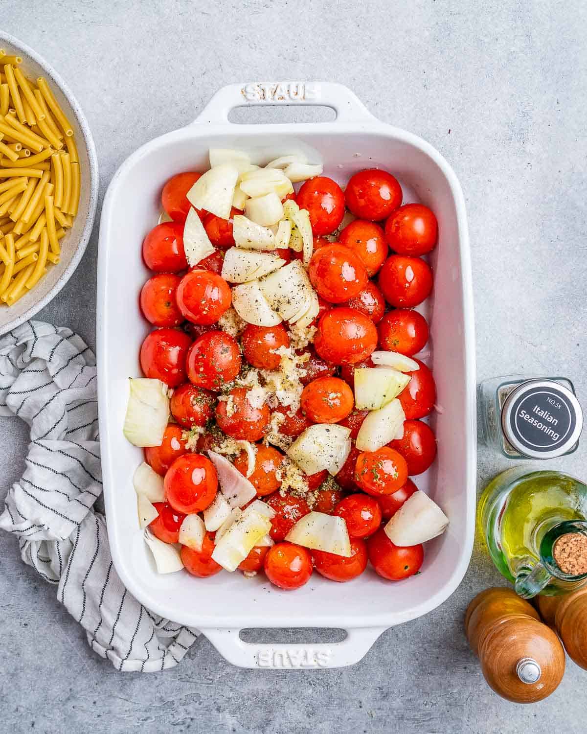 Tomatoes and onions in a white baking dish.