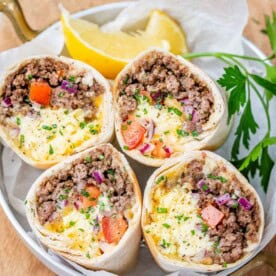 Four halves of a breakfast burrito standing up to show the ingredients on a white plate.