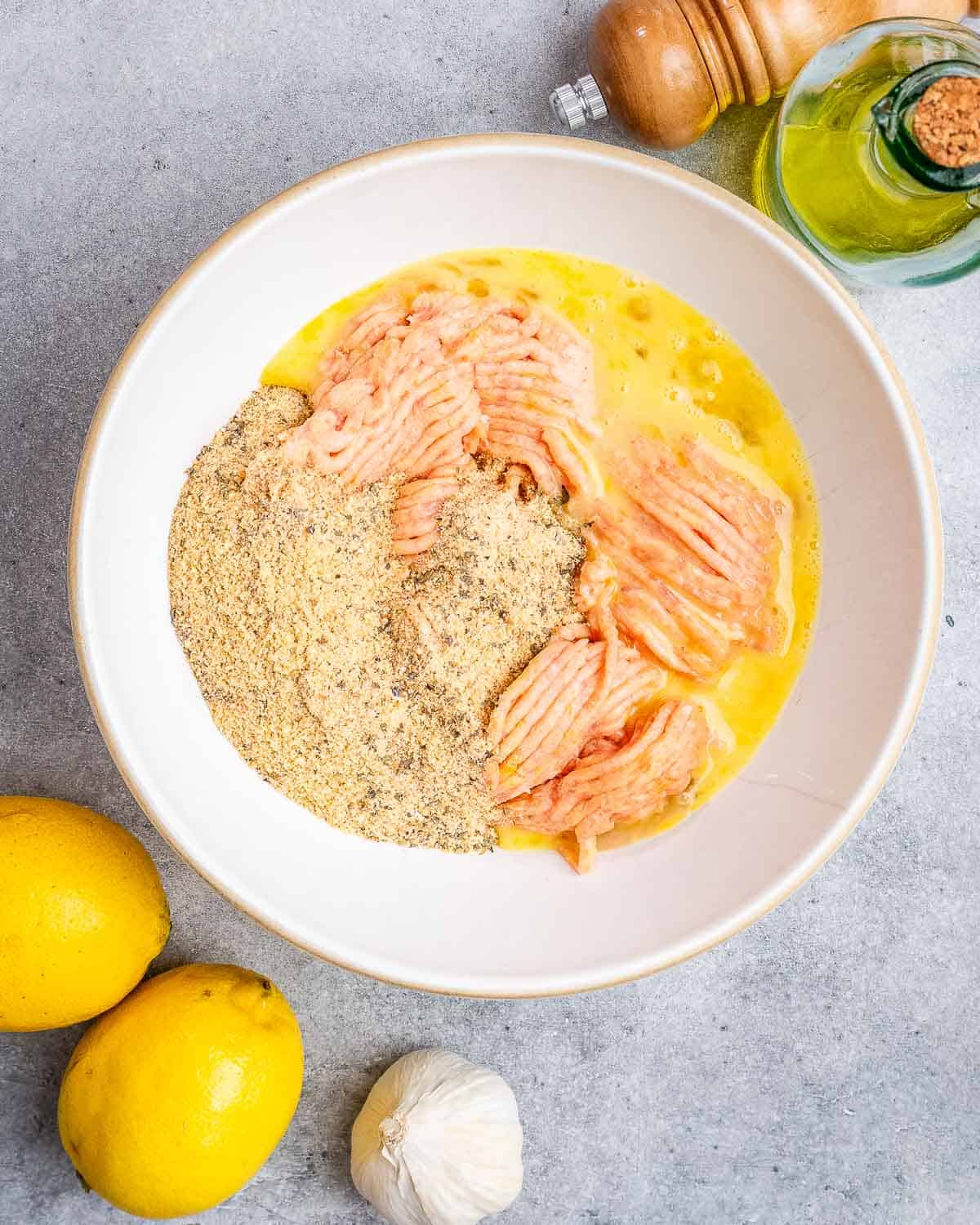 A bowl filled with ground chicken and other ingredients. 