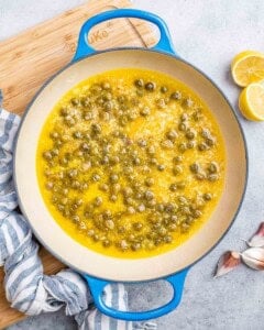 Capers and lemon juice simmering in a pot.