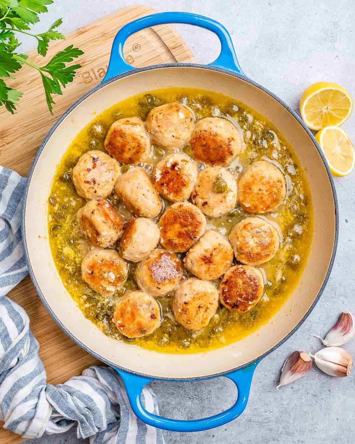 Meatballs and capers in a pot on the stove.