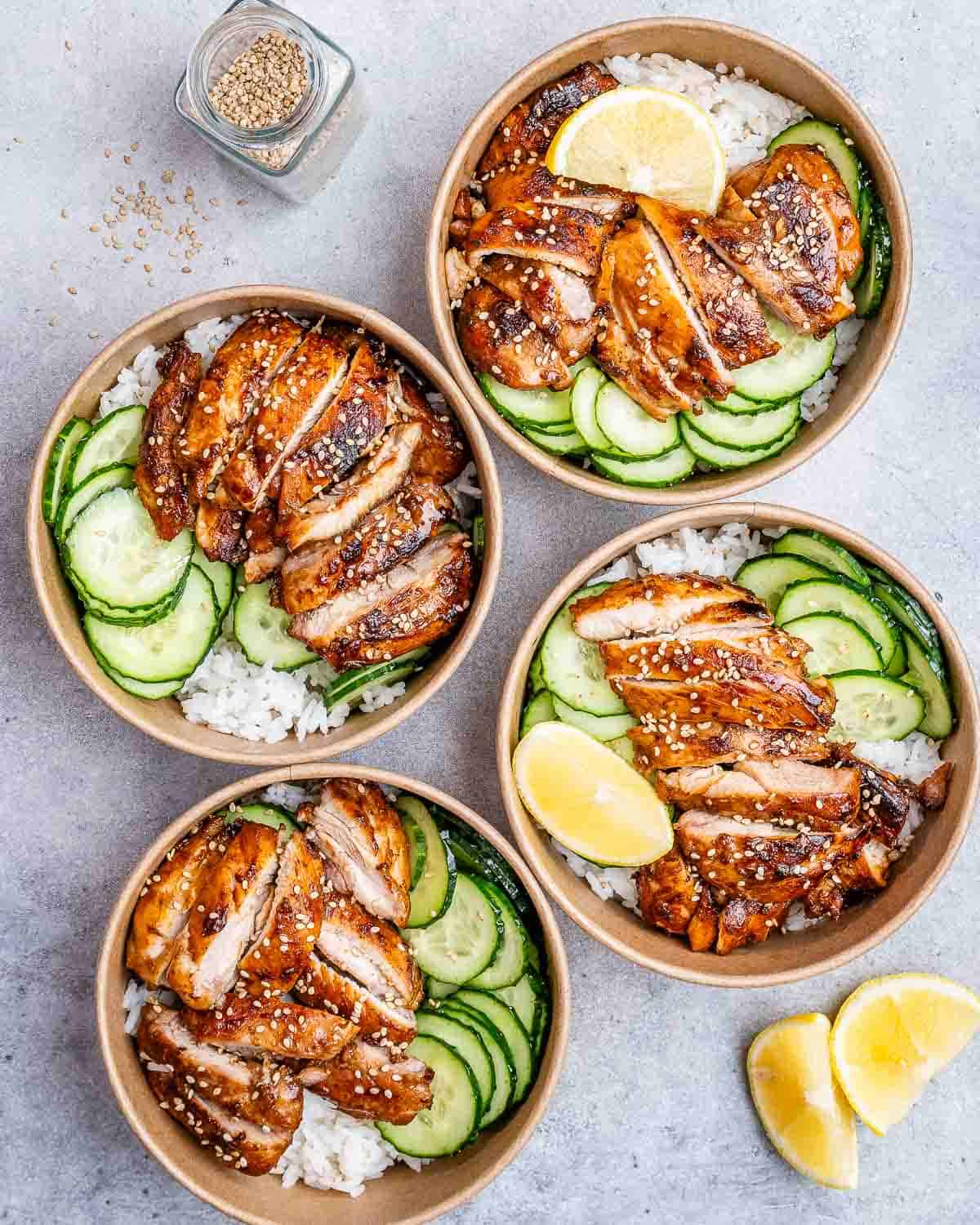 Four bowls of chicken and rice on a gray background.