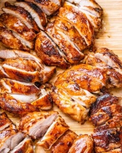 Sliced cooked chicken thighs on a cutting board.