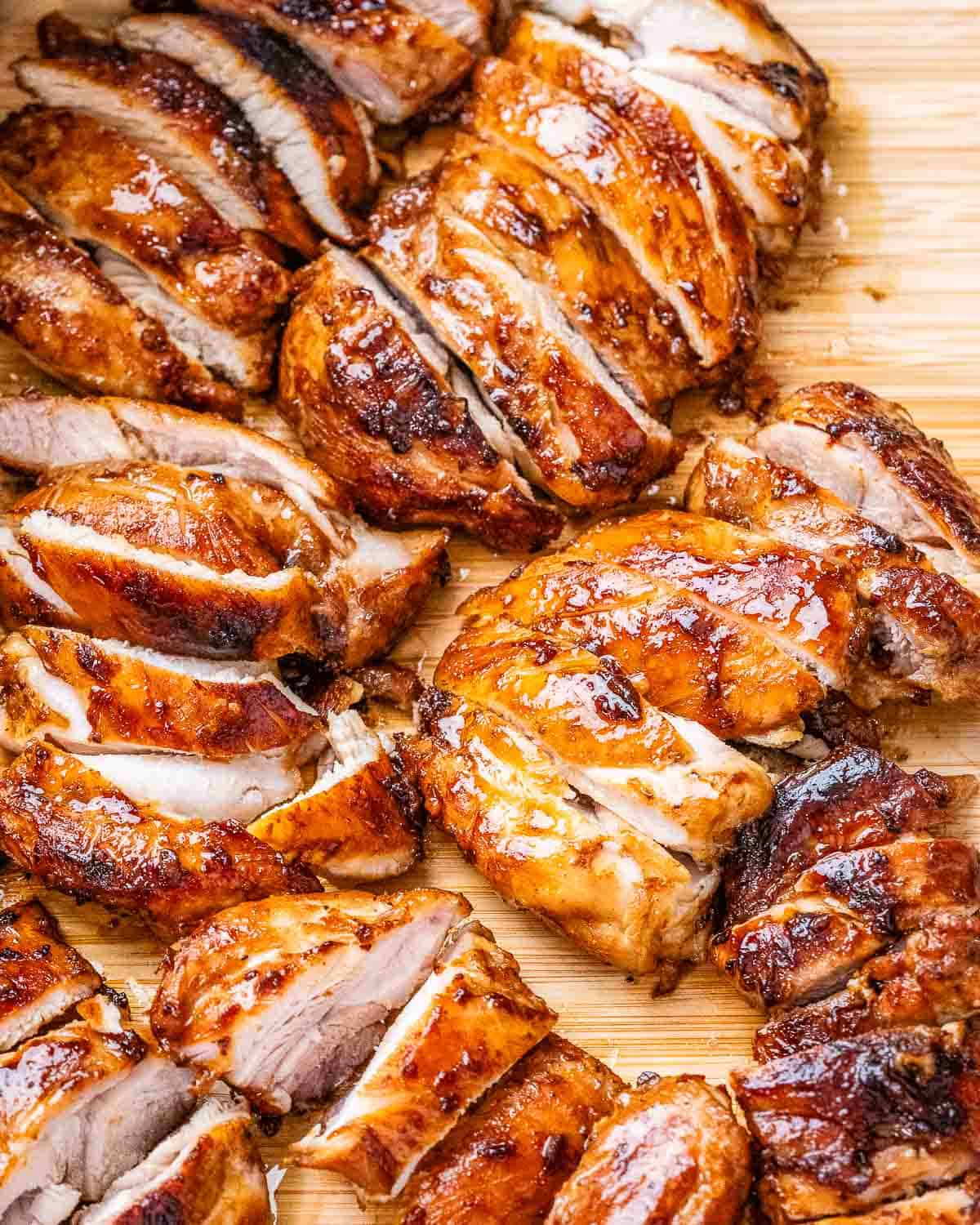 Sliced cooked chicken thighs on a cutting board.