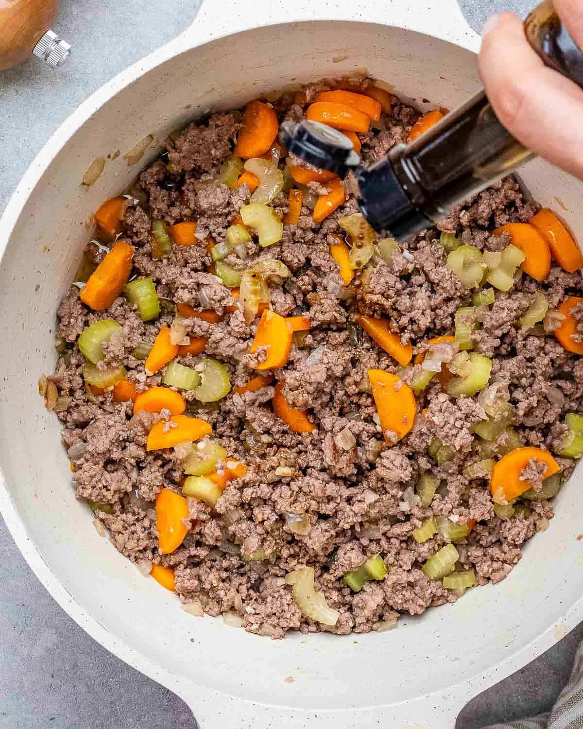 cooking ground beef with onions, celery, and carrots in round pot