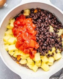 round white pot with tomatoes, potatoes, black beans