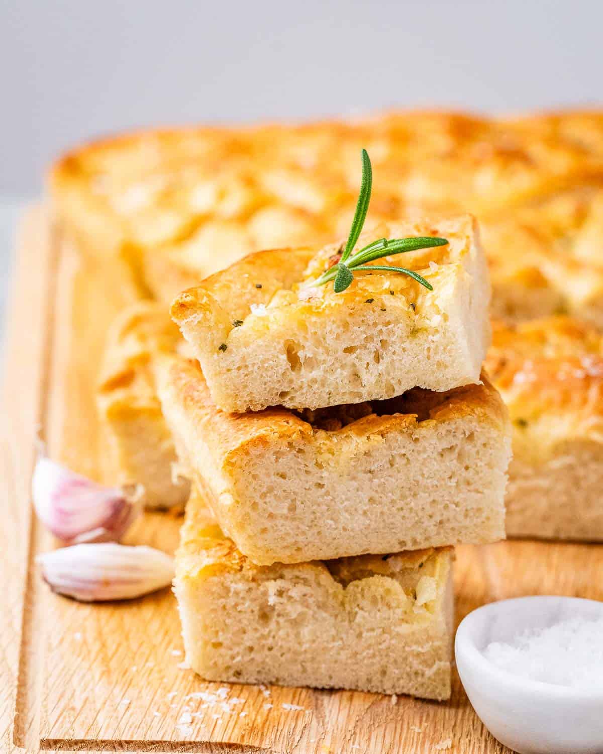 three slices of focaccia bread with rosemary and garlic on cutting board