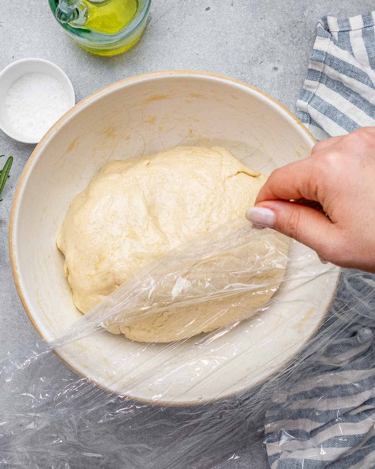 top view of focaccia dough ball in bowl with plastic wrap