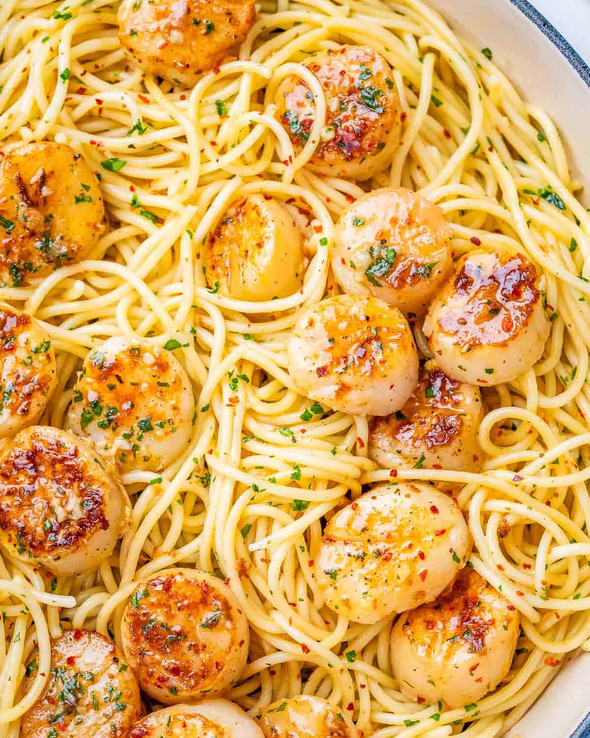 A close-up of scallop pasta with perfectly seared scallops and fresh herbs tossed with spaghetti.