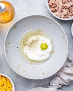 Small bowl with mayonnaise, lemon juice, white wine vinegar, wasabi, and seasoning before mixing.