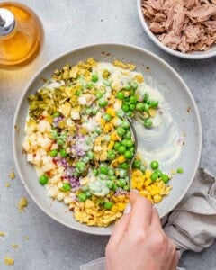Spoon mixing ingredients into creamy dressing in a bowl for the fish salad.
