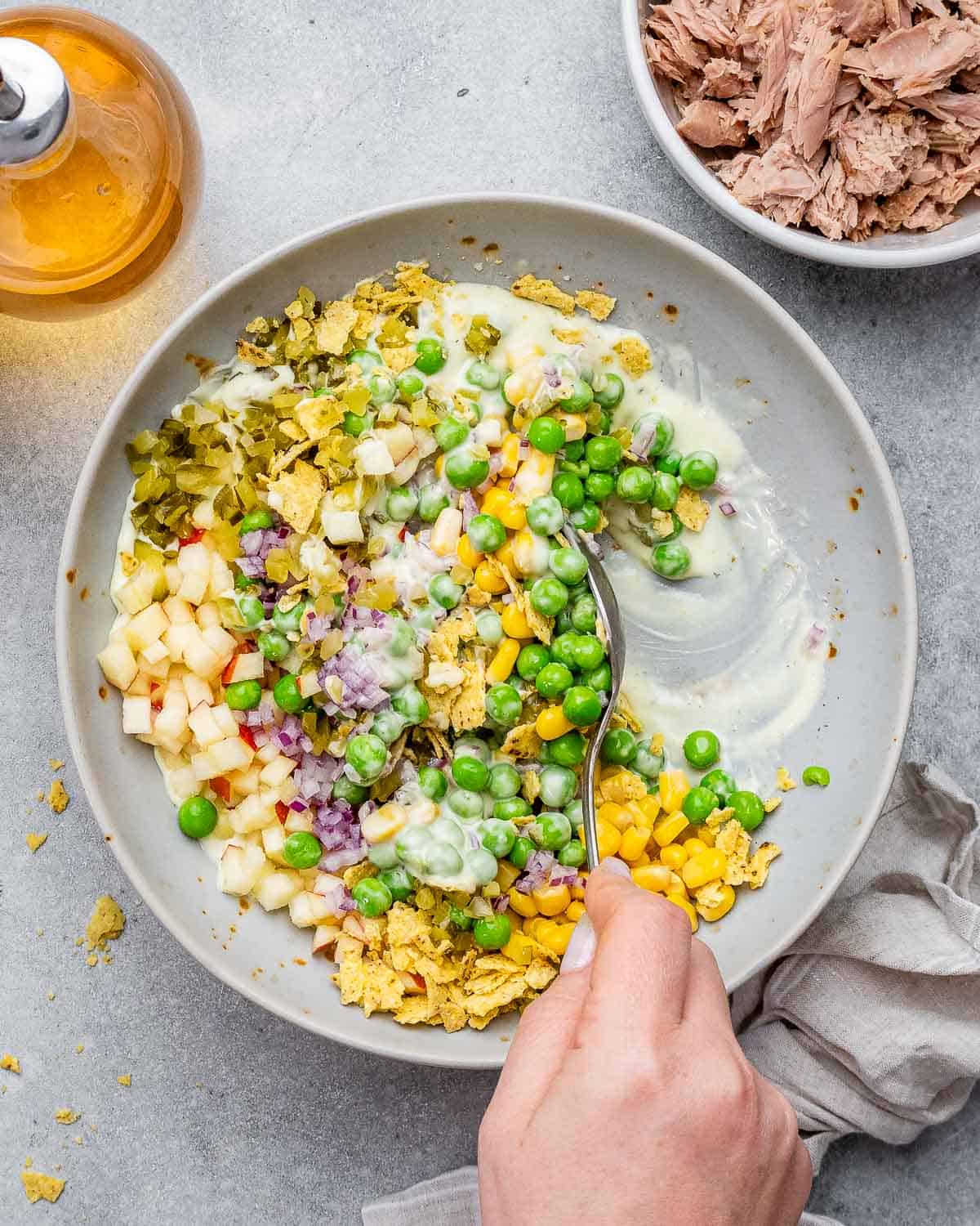 Spoon mixing ingredients into creamy dressing in a bowl for the fish salad.