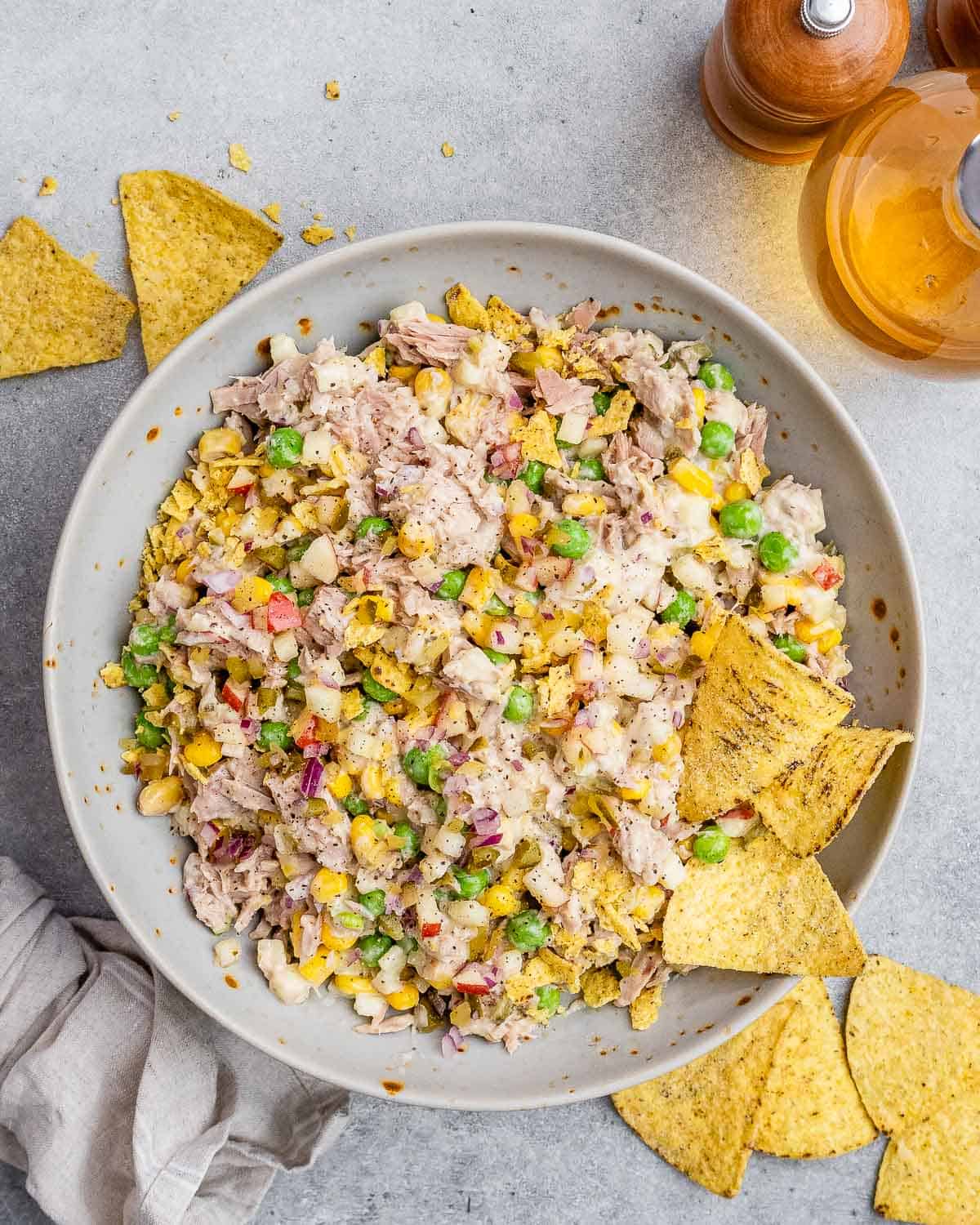 Tuna salad in a gray bowl surrounded by tortilla chips.