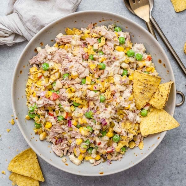 A round bowl with tuna salad and two tortilla chips in it.