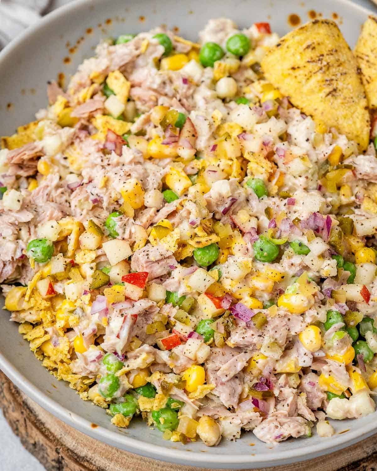 Overhead view of tuna salad with colorful vegetables and crushed jalapeño chips.