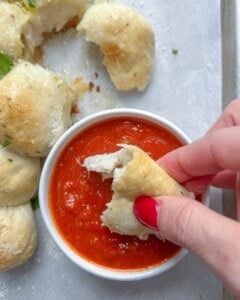 cheese ball bread being dipped in marinara sauce.