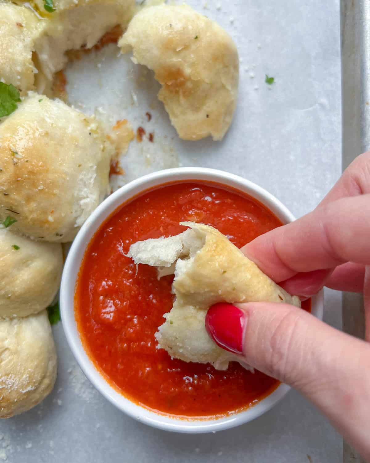 cheese ball bread being dipped in marinara sauce.