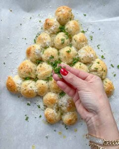 parsley and parmesan cheese being garnished over the baked cheese ball tree.