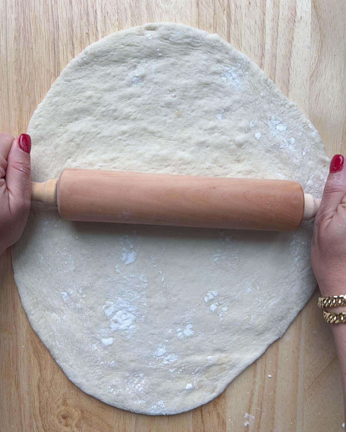 Dough being rolled out on a flat cutting board.