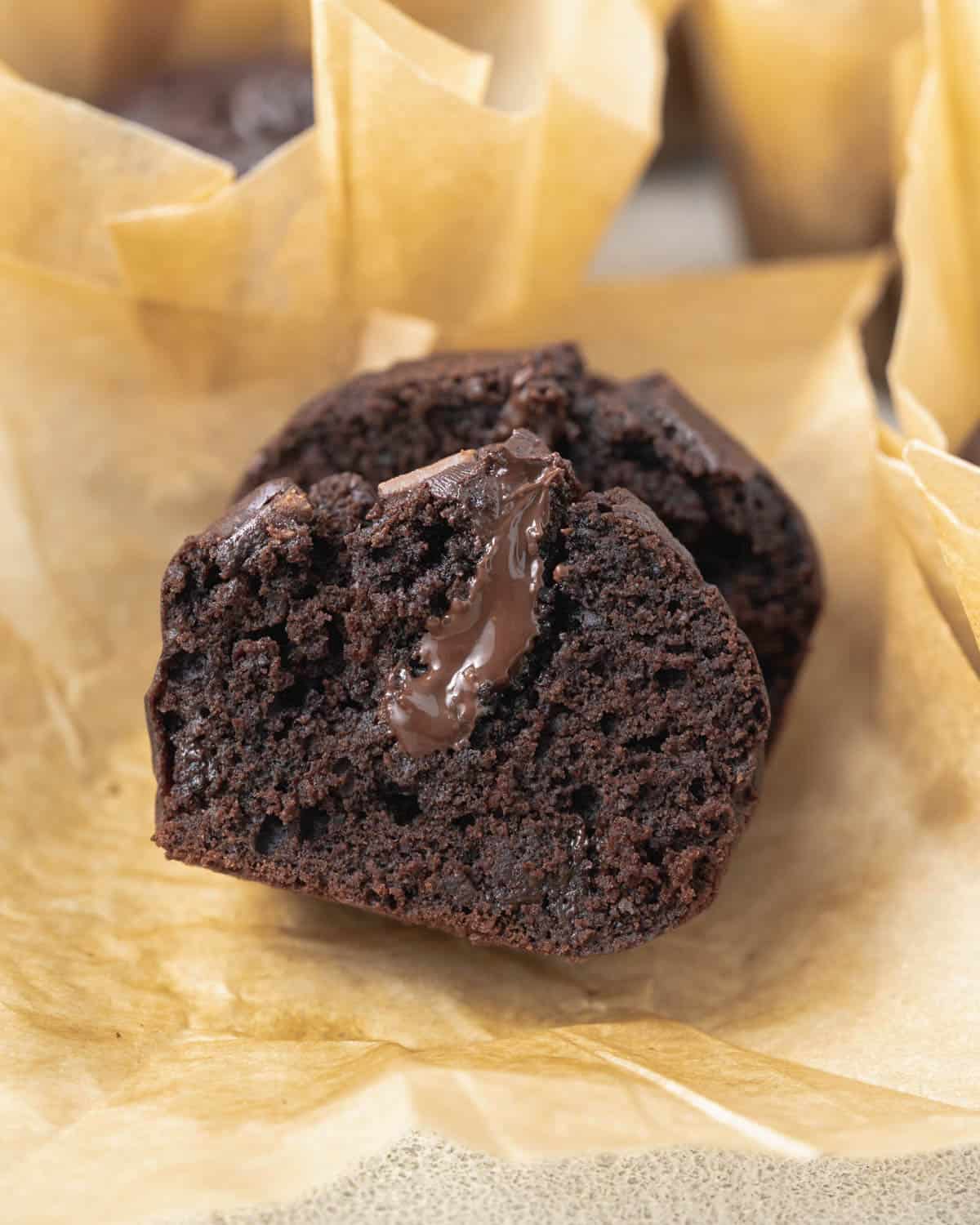 Chocolate muffins cut in half in parchment paper with chocolate ganache in the middle.