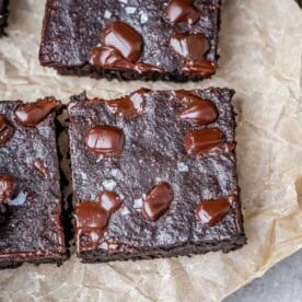 brownie squares on a parchment paper on a cutting board.