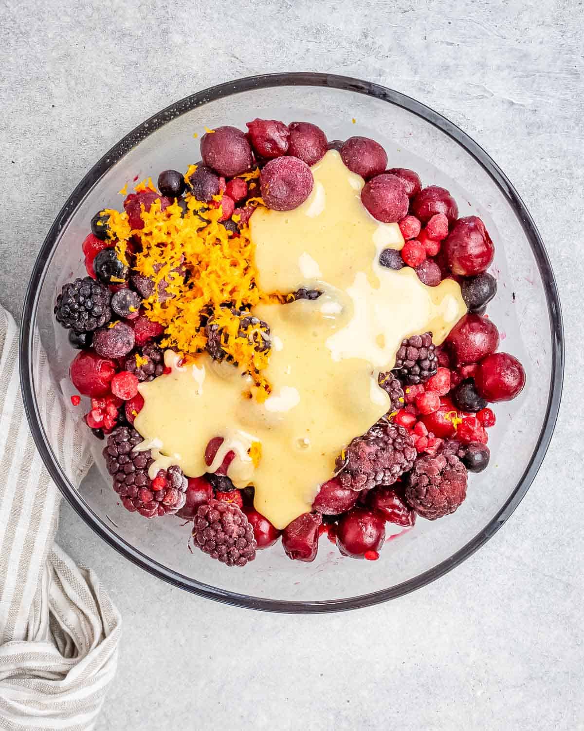 frozen berries in a bowl with orange zest and honey added.