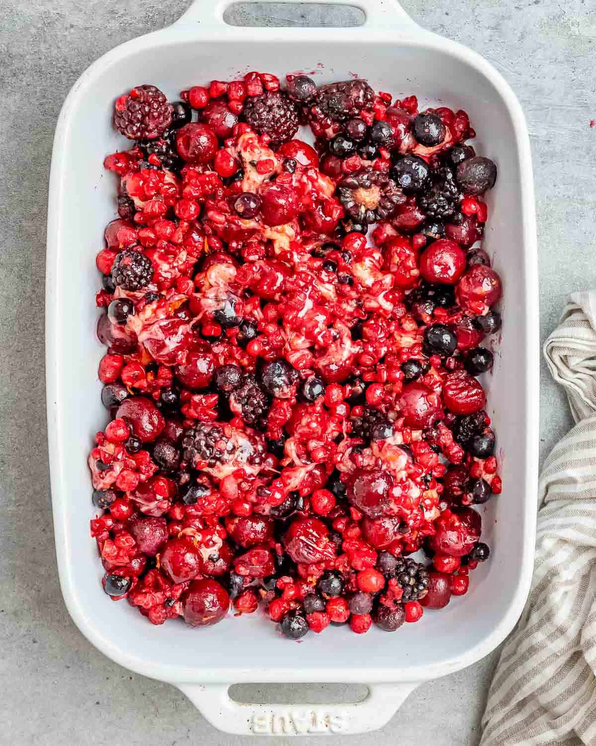 berry mixture added to a white baking dish.