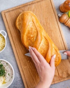 Hand-slicing a french bread in the middle.