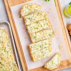 garlic bread sliced lengthwise on a cutting board.