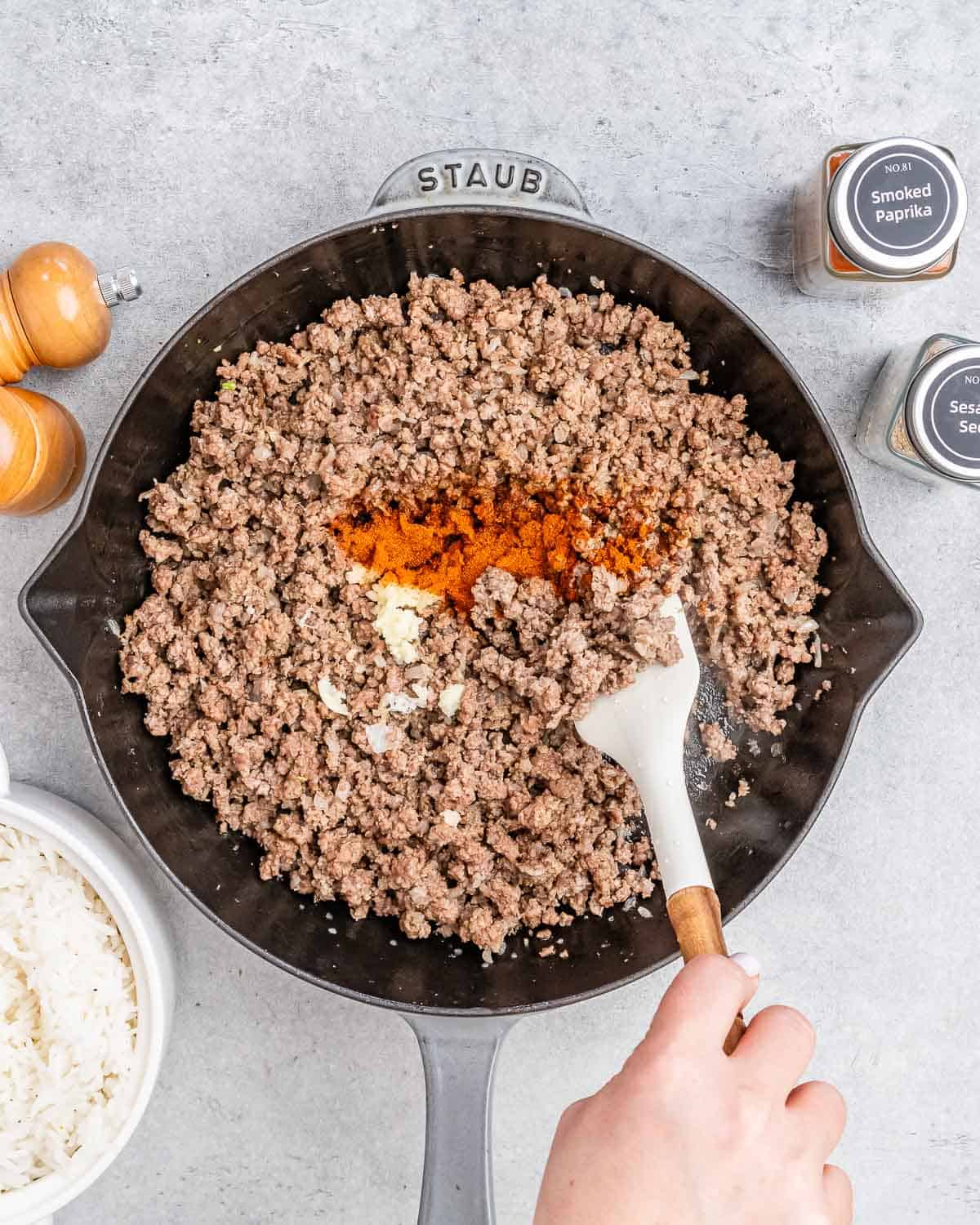 Stirring in spices to ground beef in a skillet.