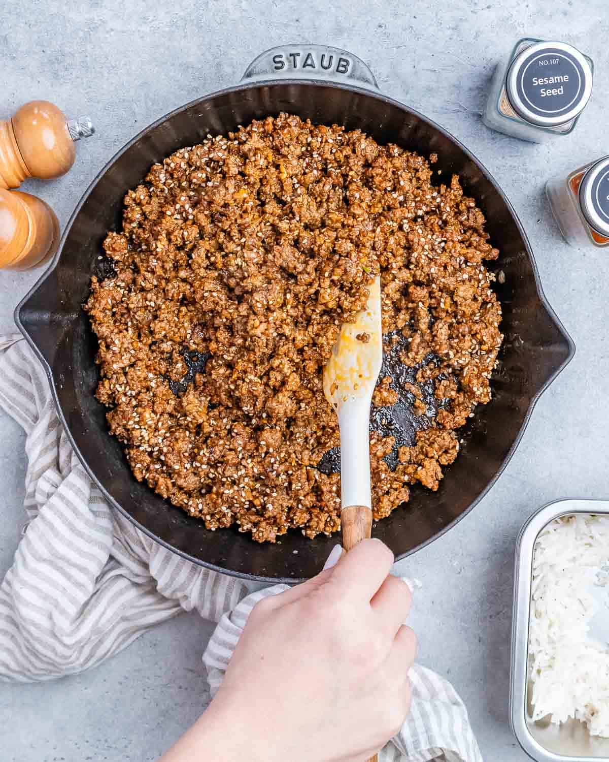 Stirring ground beef in a skillet with a white spatula.