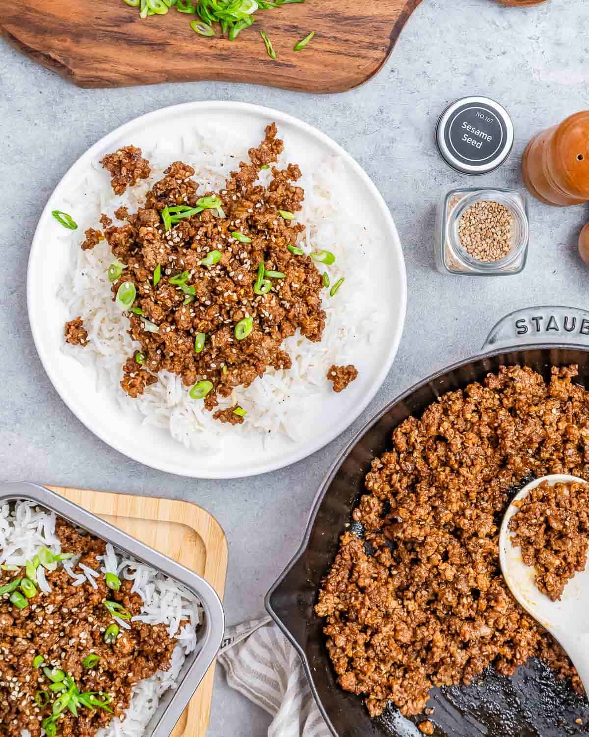 A plate of ground beef and rice with a skillet and serving spoon on the side.