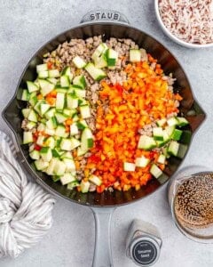 Brightly colored vegetables on top of ground turkey in a skillet.